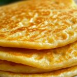 Panqueque de avena sin azúcar ni harina servido con frutas frescas y yogur natural sobre un plato blanco.