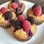 Muffins caseros de cottage con frutos rojos y ralladura de limón sobre una rejilla enfriadora.