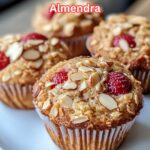Muffins saludables de cottage con fresas y almendras laminadas recién horneados sobre una superficie rústica.