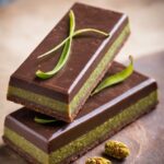 Tabletas de chocolate rellenas de pistacho y kadaif crujiente, presentadas en una bandeja con decoración oriental.