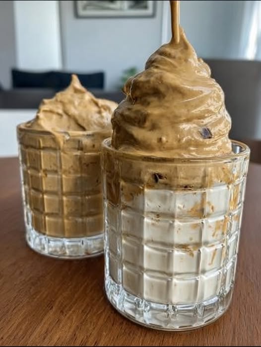 Postre cremoso de café servido en un vaso pequeño, espolvoreado con cacao en polvo.