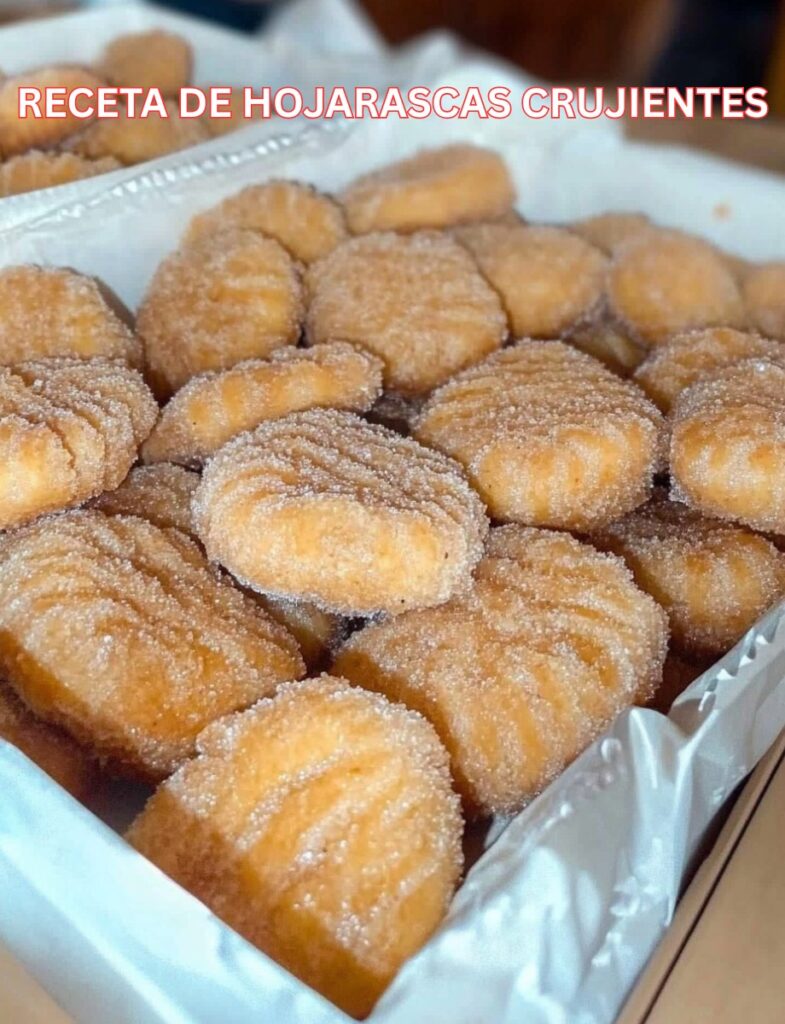 Hojarascas crujientes recién horneadas, cubiertas de azúcar con canela, servidas sobre una bandeja de madera.