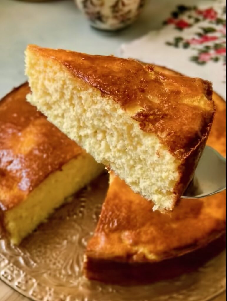 Pan de elote sin harina recién horneado, de textura húmeda, color dorado y servido en rebanadas sobre una mesa de madera rústica.