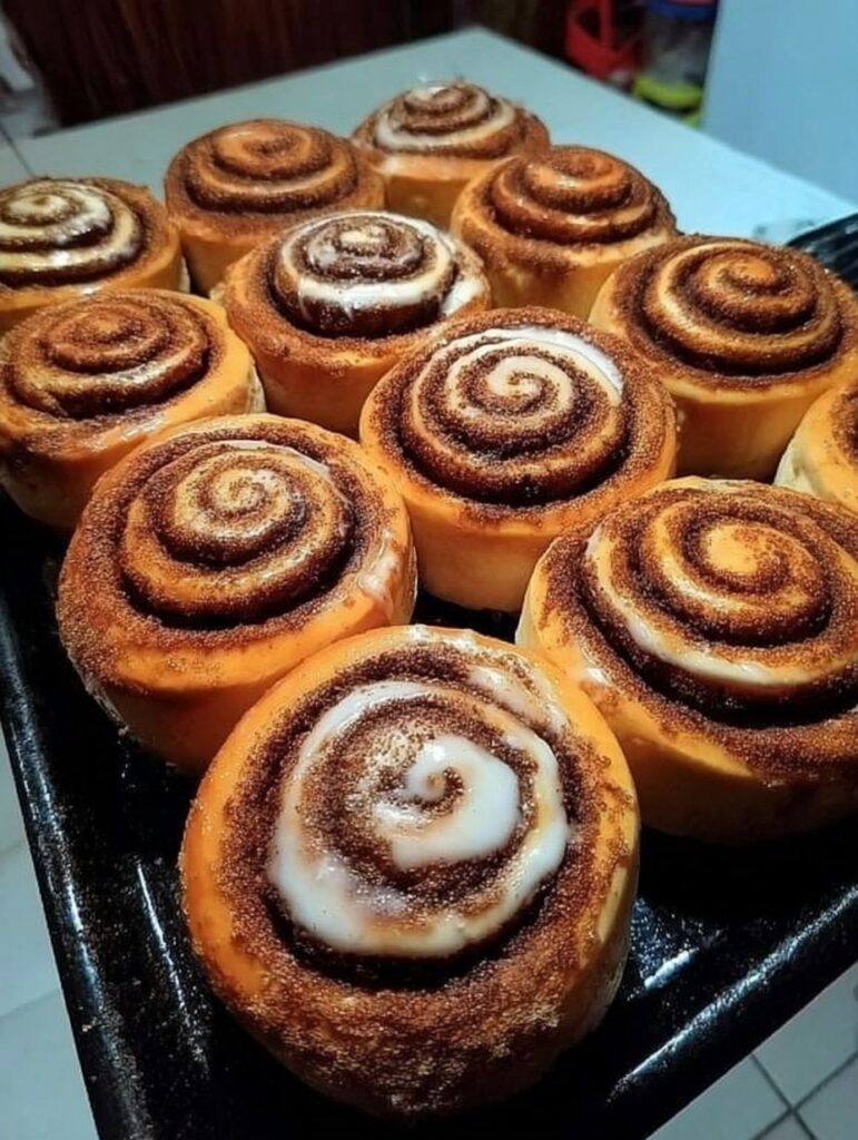 Roles de canela recién horneados, doraditos, con relleno de canela y azúcar derretido.