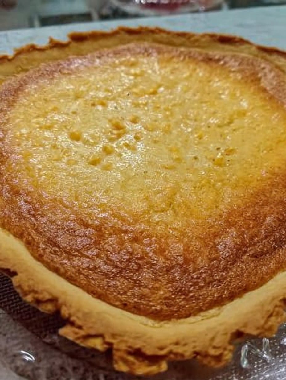 Pay de elote cremoso sobre base de galleta María, dorado y recién horneado, servido en rebanadas.