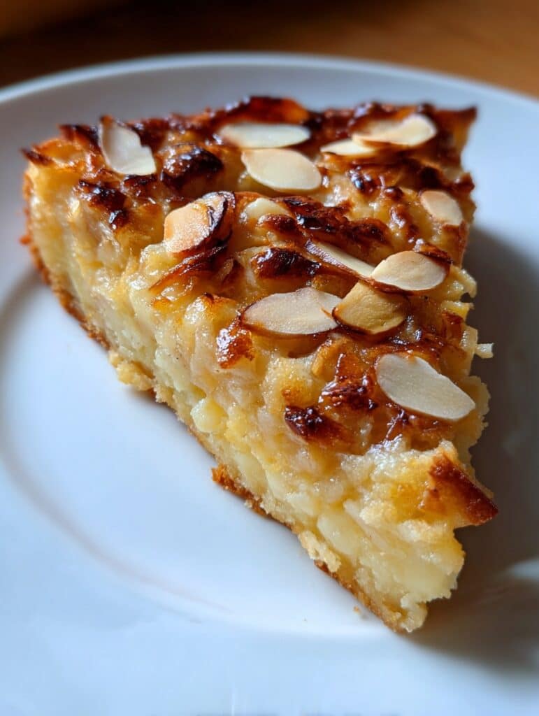 Tarta rústica de manzana y almendra sin harina, decorada con almendras laminadas y horneada hasta dorar.