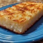 Pan de coco keto esponjoso recién hecho en microondas, servido en un plato blanco con café.