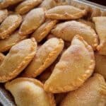 Empanaditas de cajeta recién horneadas, doradas y rellenas de dulce de leche.