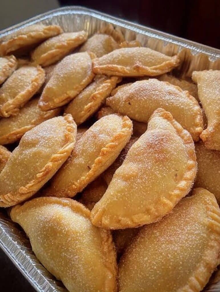 Empanaditas de cajeta recién horneadas, doradas y rellenas de dulce de leche.