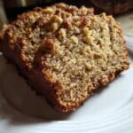 Pan de avena y manzana sin harina recién horneado, decorado con nueces y servido en rebanadas sobre una mesa rústica.