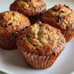 Muffins caseros de plátano, cacao y avena, sin azúcar ni harina, recién horneados y servidos en un plato blanco.