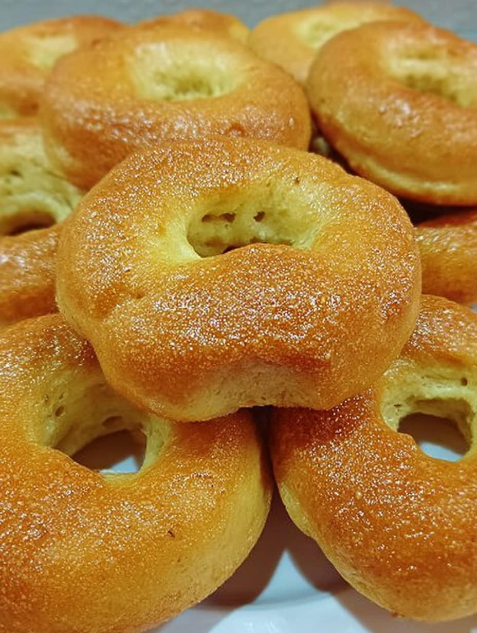 Roscos de naranja al horno caseros, dorados y espolvoreados con azúcar, listos para servir en una bandeja.