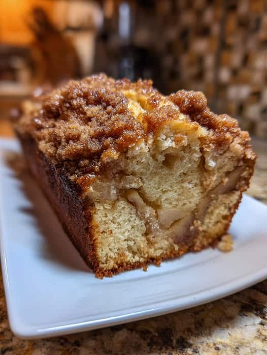 Budín rápido de manzana con crumble de canela recién horneado en un molde rectangular, con superficie dorada y crujiente.