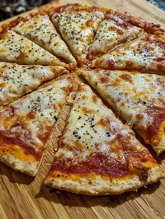 Pizza de avena saludable con queso derretido, vegetales frescos y albahaca, servida en una mesa de madera.