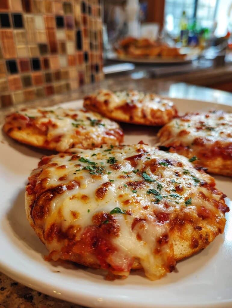 Mini pizzas caseras de avena recién horneadas con queso derretido, salsa de tomate y albahaca fresca, servidas en una mesa para compartir en familia.