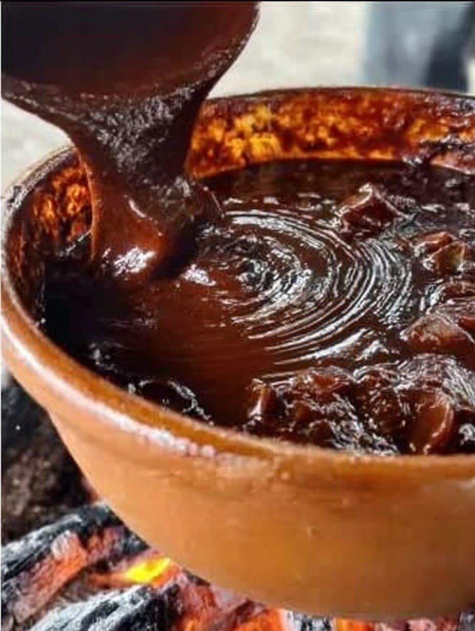 Mole casero servido con arroz rojo y pollo, decorado con ajonjolí tostado.