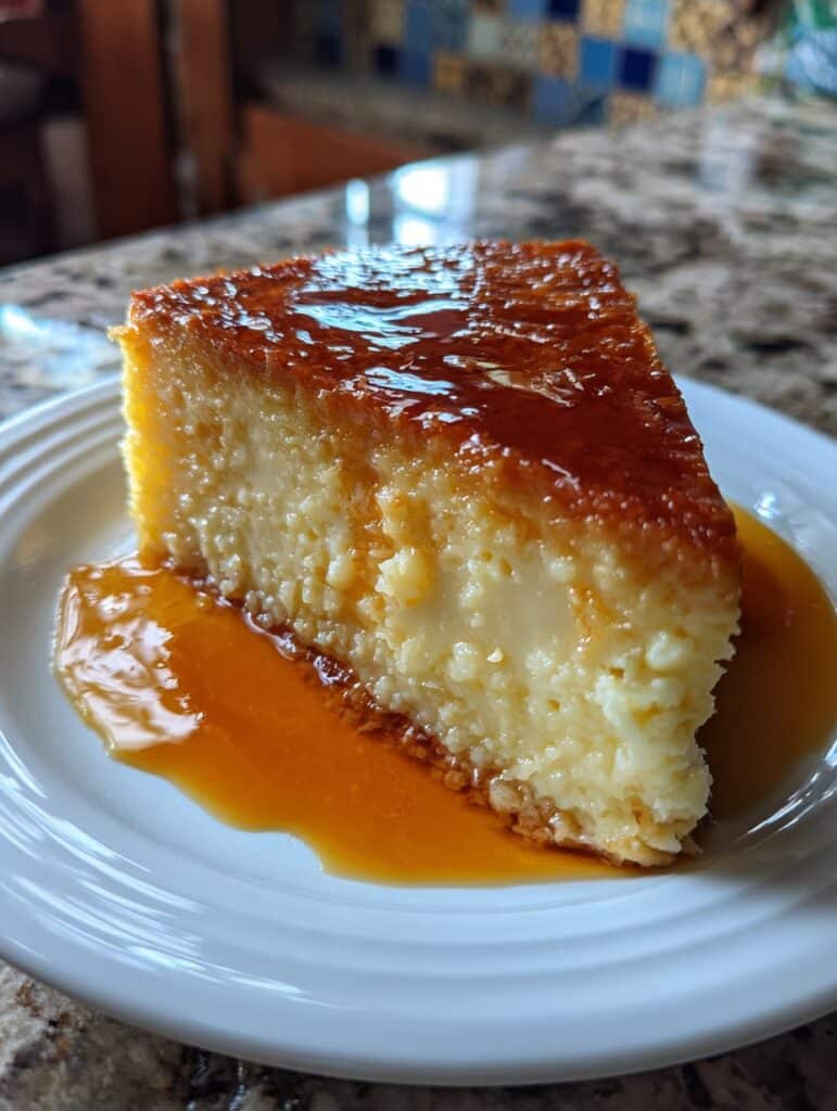 Budín mágico de coco y leche sobre un plato blanco, con caramelo y coco rallado encima.