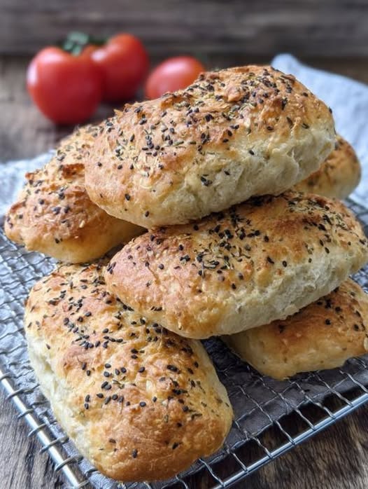 Mini panecillos salados de yogur griego y harina de avena recién horneados, decorados con semillas de sésamo y chía sobre una bandeja de madera.