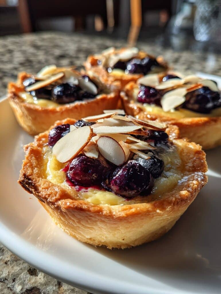 “Mini tartitas de requesón y frutos rojos recién horneadas sobre una bandeja.”